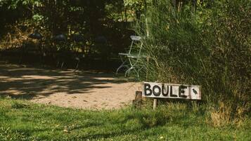 A sign labeled "BOULE" in a grassy area with trees and a metal structure in the background.