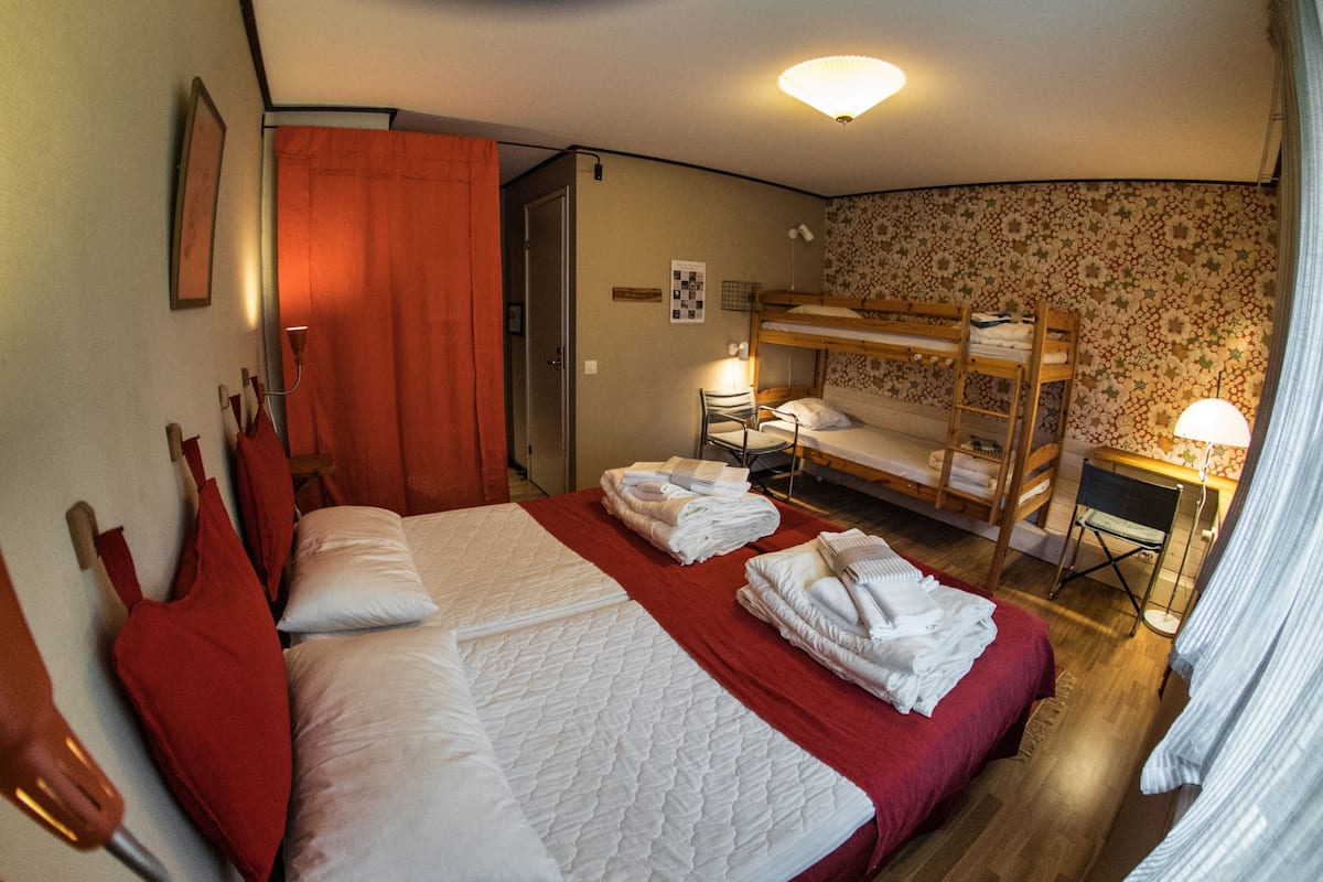 A hotel room with a large bed, a bunk bed, a desk, and a chair.