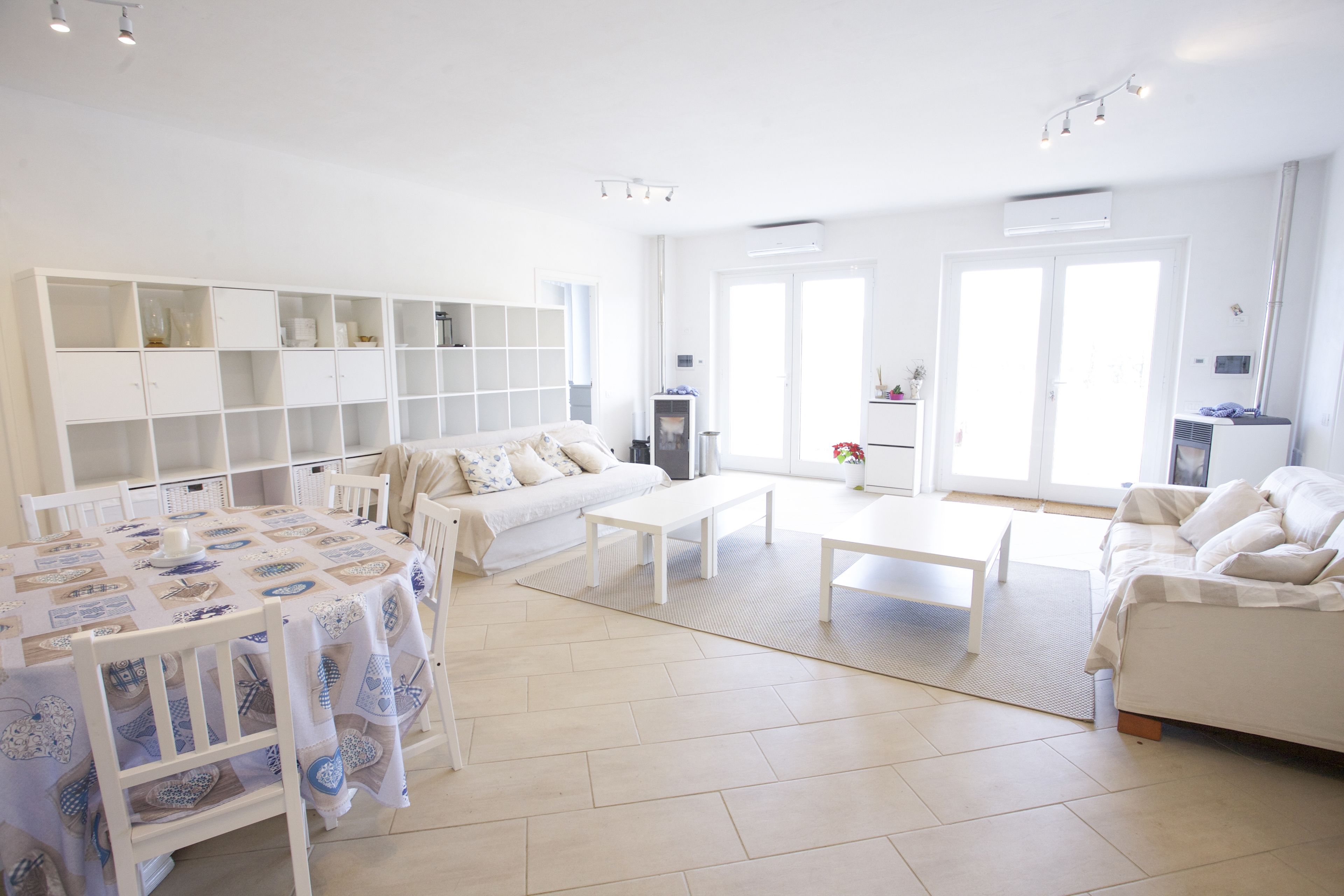 A spacious living area with a sofa, a dining table, and a white cabinet.