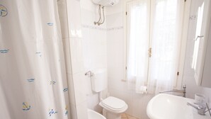 Et badeværelse med toilet, bidet, vask og brusebad.