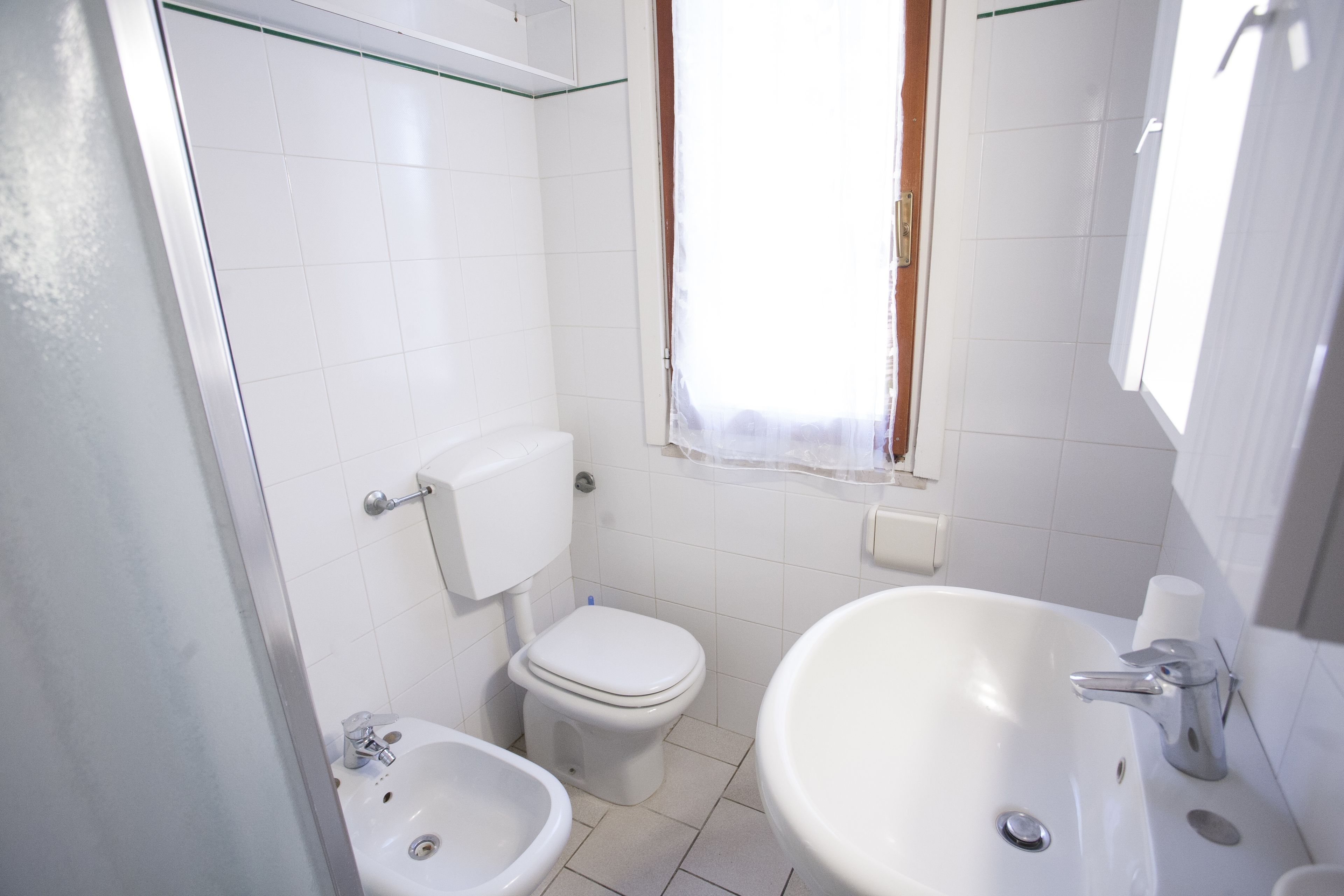 A small, clean bathroom with a toilet, bidet, and sink.