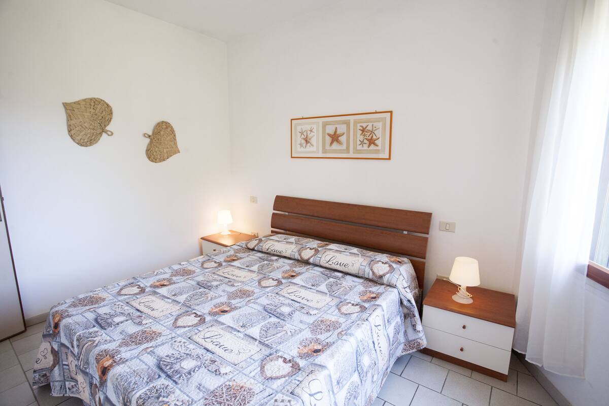 Une chambre à coucher comprenant un lit, des tables de chevet, une commode, une lampe et des éléments décoratifs sur les murs.