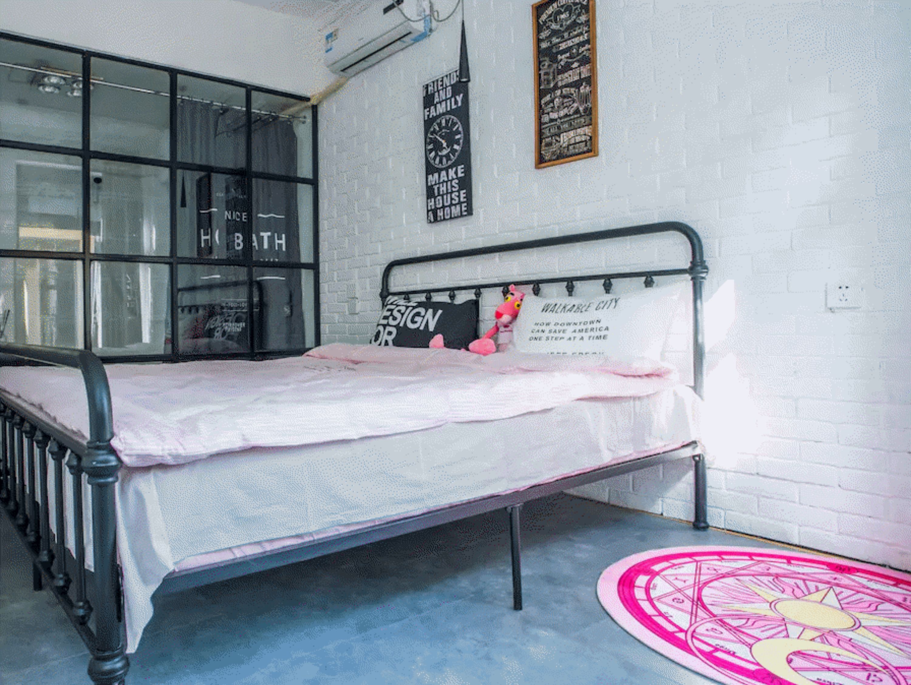 Un letto singolo con struttura in metallo, una coperta rosa e un peluche appoggiato alla testiera. Sul muro dietro il letto, una lavagna con scritte motivazionali.