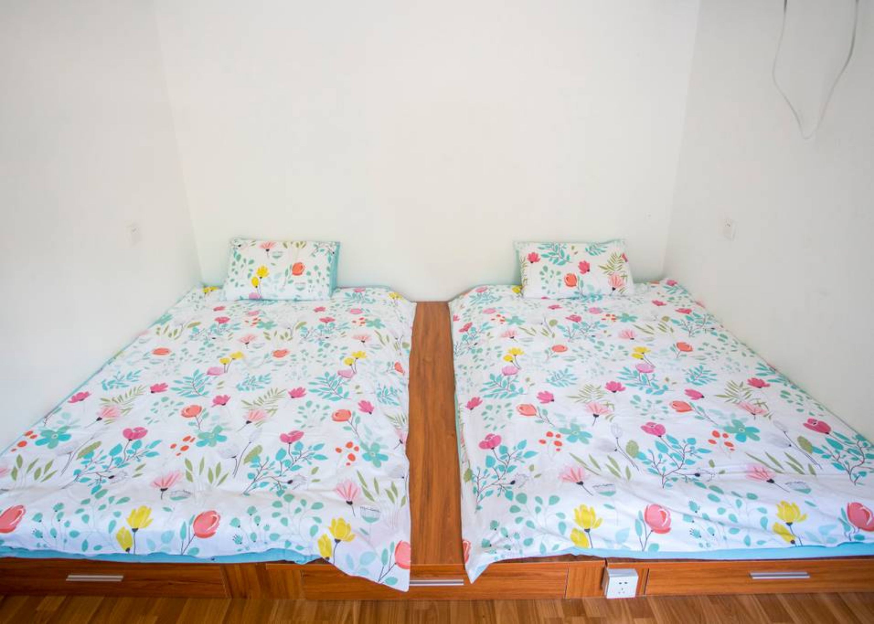 A twin room with two beds, each with floral bedding and matching pillows.