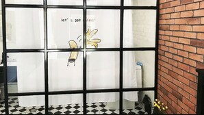 A room with a black and white checkered floor, a brick wall, and a window with a message and a cartoon character. - Snail Home Inn (Huairou)