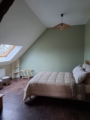 A bedroom with a sloped ceiling, a skylight, a bed with pillows, a bedside table, and a hanging light fixture. - Le Clos des Pensées (Saint-Sauveur-d'Emalleville)