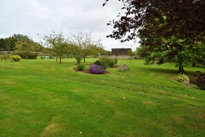 A well-maintained grassy area with trees and a few purple flowering bushes. - Le Clos des Pensées (Saint-Sauveur-d'Emalleville)