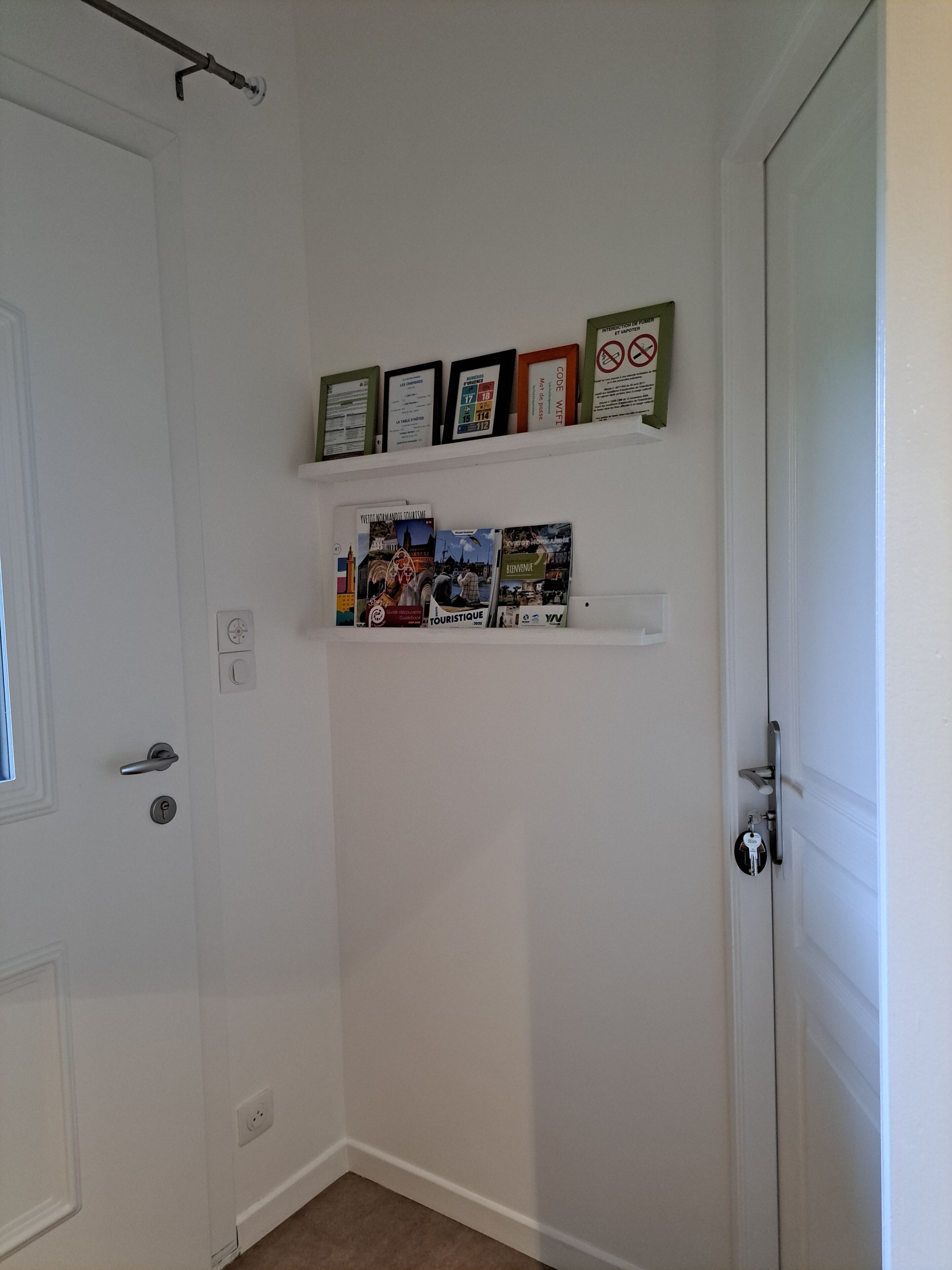 Una puerta blanca con un picaporte, un interruptor de luz y un enchufe en la pared.