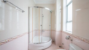 Un baño con ducha de vidrio, inodoro y ventana.