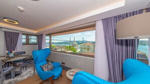 Una camera moderna con un balcone, un'area pranzo e vista su un ponte e sullo skyline della città.