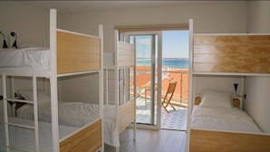 Et værelse med køjesenge, en skydedør til en balkon med udsigt over stranden.