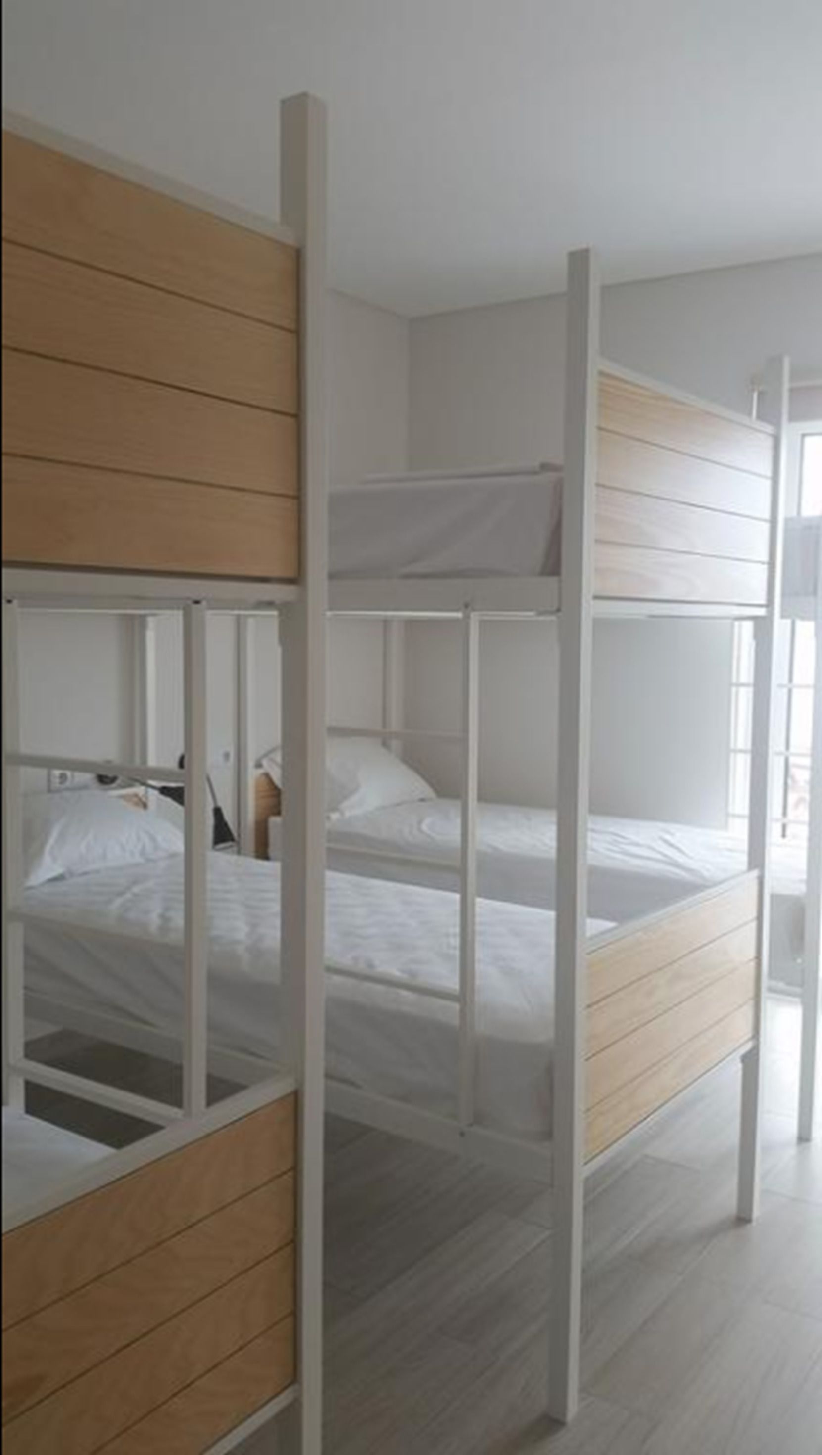 Une chambre avec des lits superposés, des lambris en bois et du linge de lit blanc.
