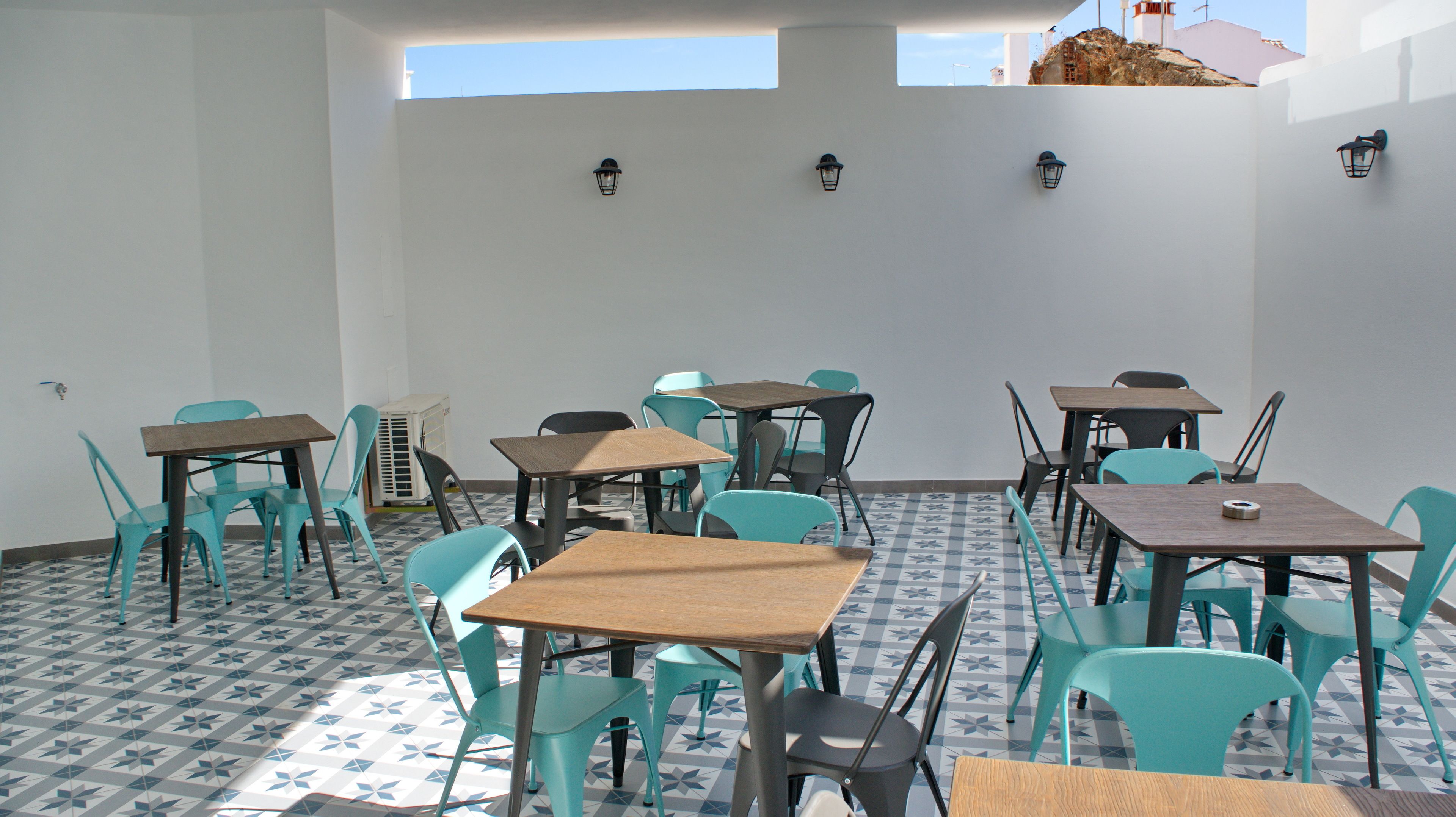An indoor dining area with tables and chairs, a patterned floor, and wall-mounted lights.