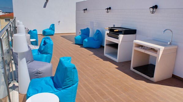 A rooftop deck with blue bean bags, a small bar area, and a white sink. - Top City Hostel & Suites (Lagos)