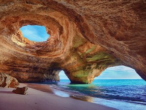 A natural rock formation with a circular opening and a beach in the foreground. - Top City Hostel & Suites (Lagos)