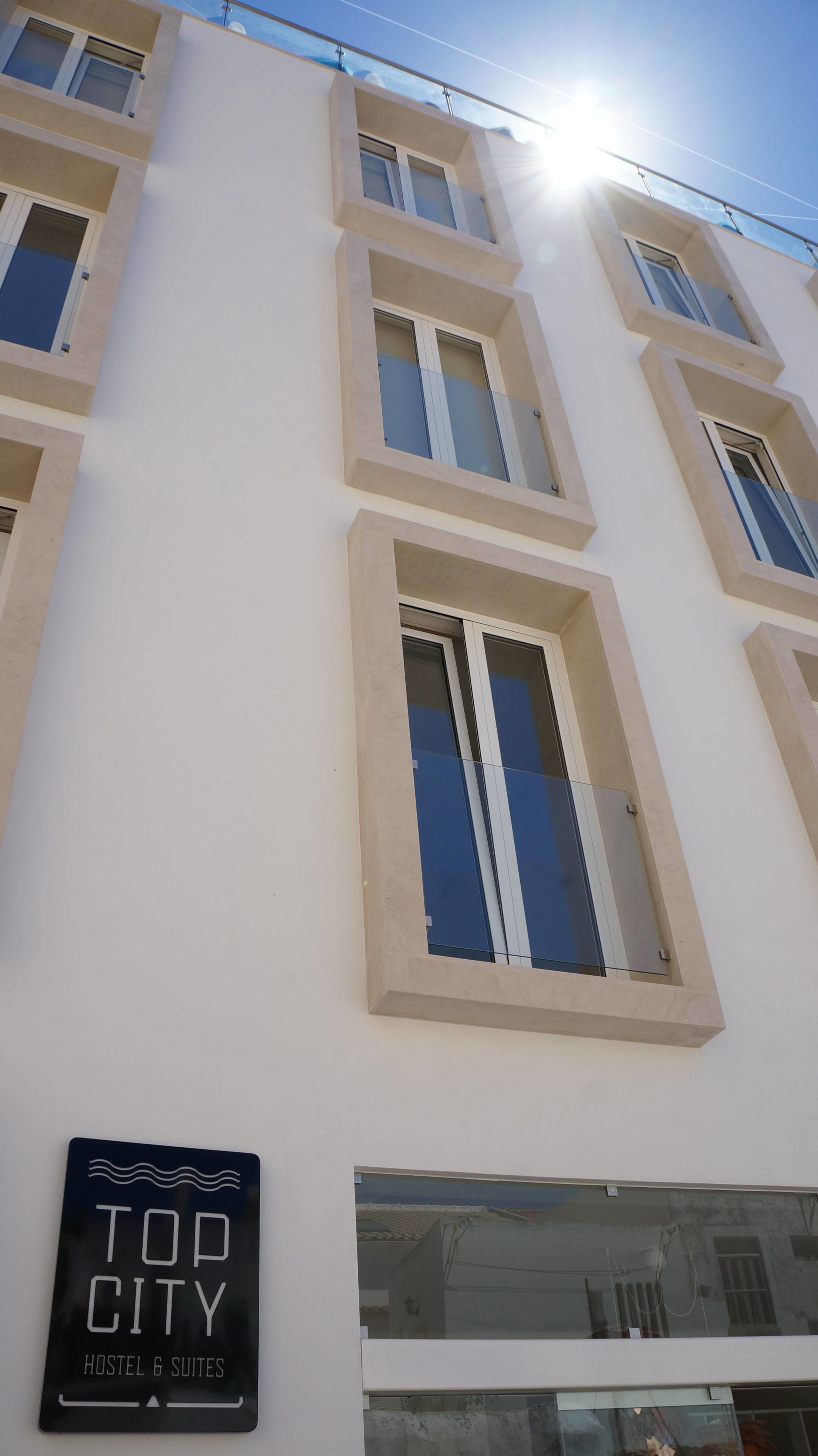 Un edifici de diversos pisos amb un cartell que indica que és un hostal i ofereix suites.