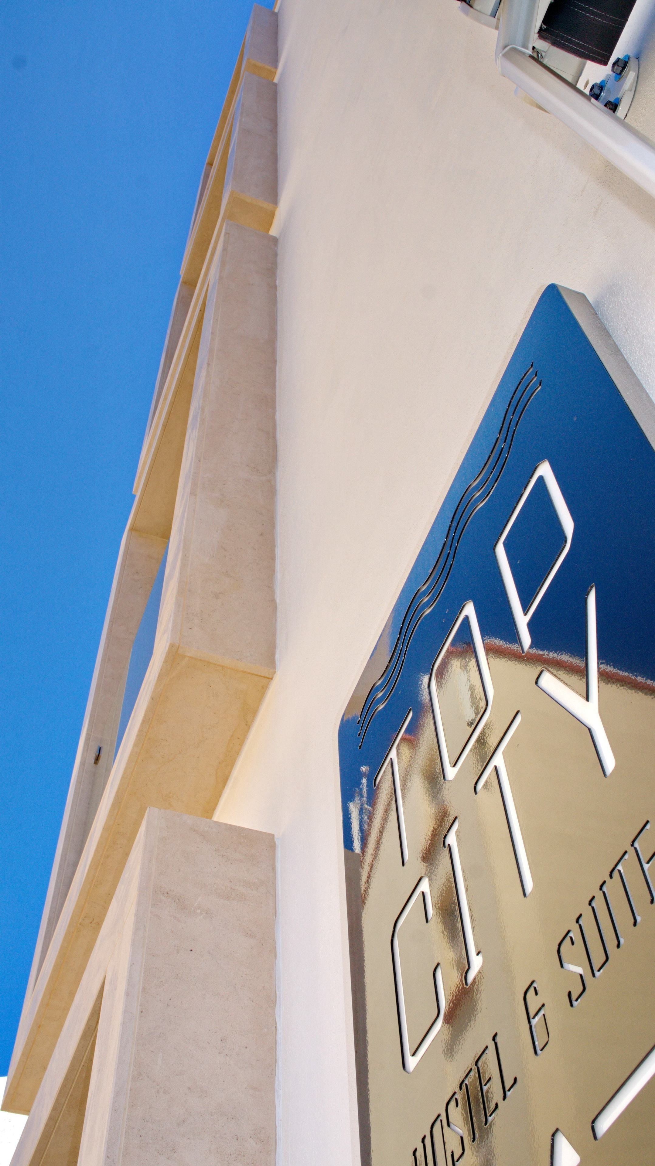 A sign for 'Top City Hotel & Suites' with a clear view of the building's architecture.