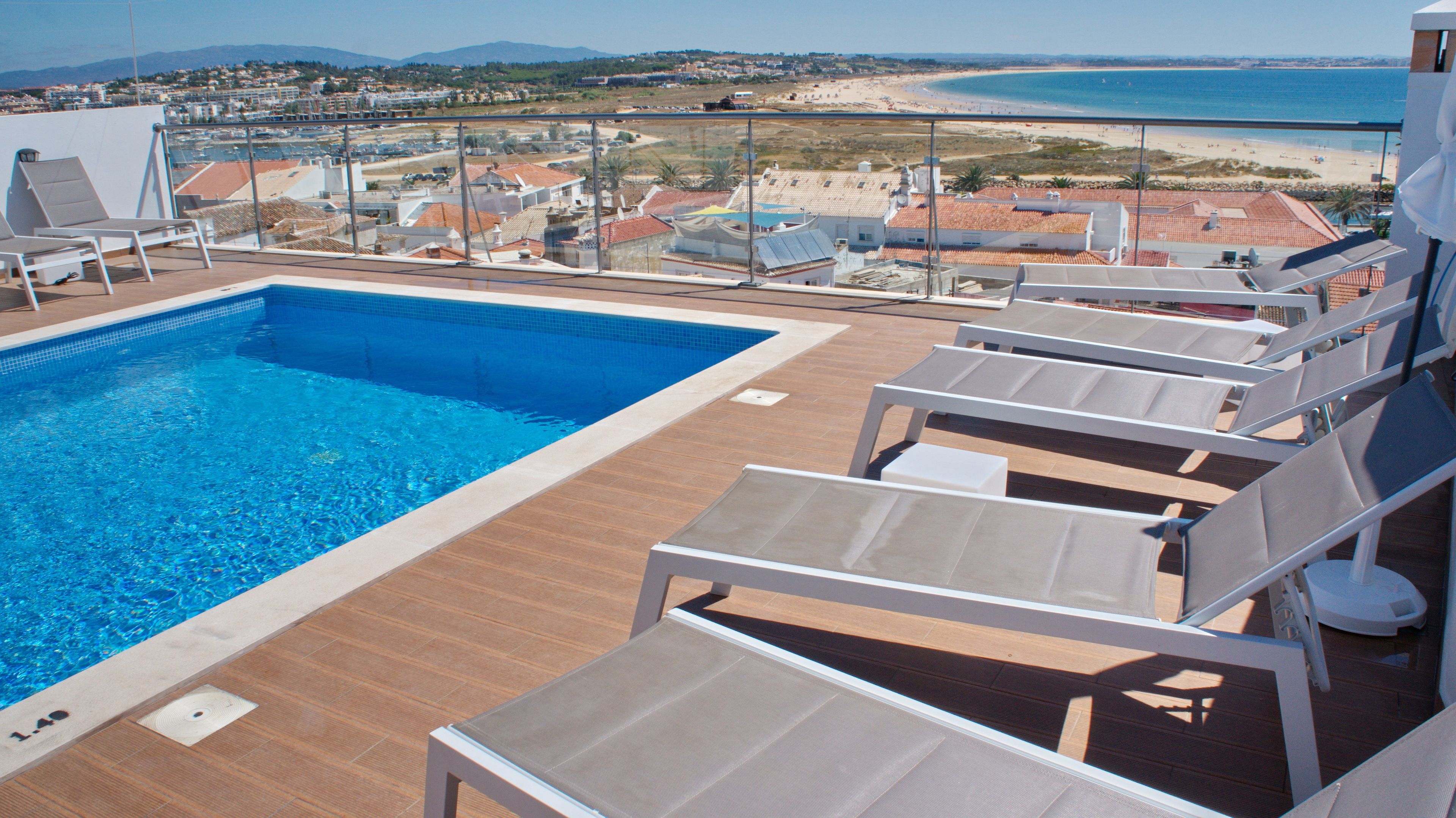 A pool area with a view of the beach and ocean.