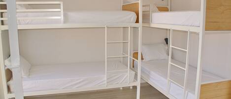 A bunk bed room with white bedding and wooden headboards.