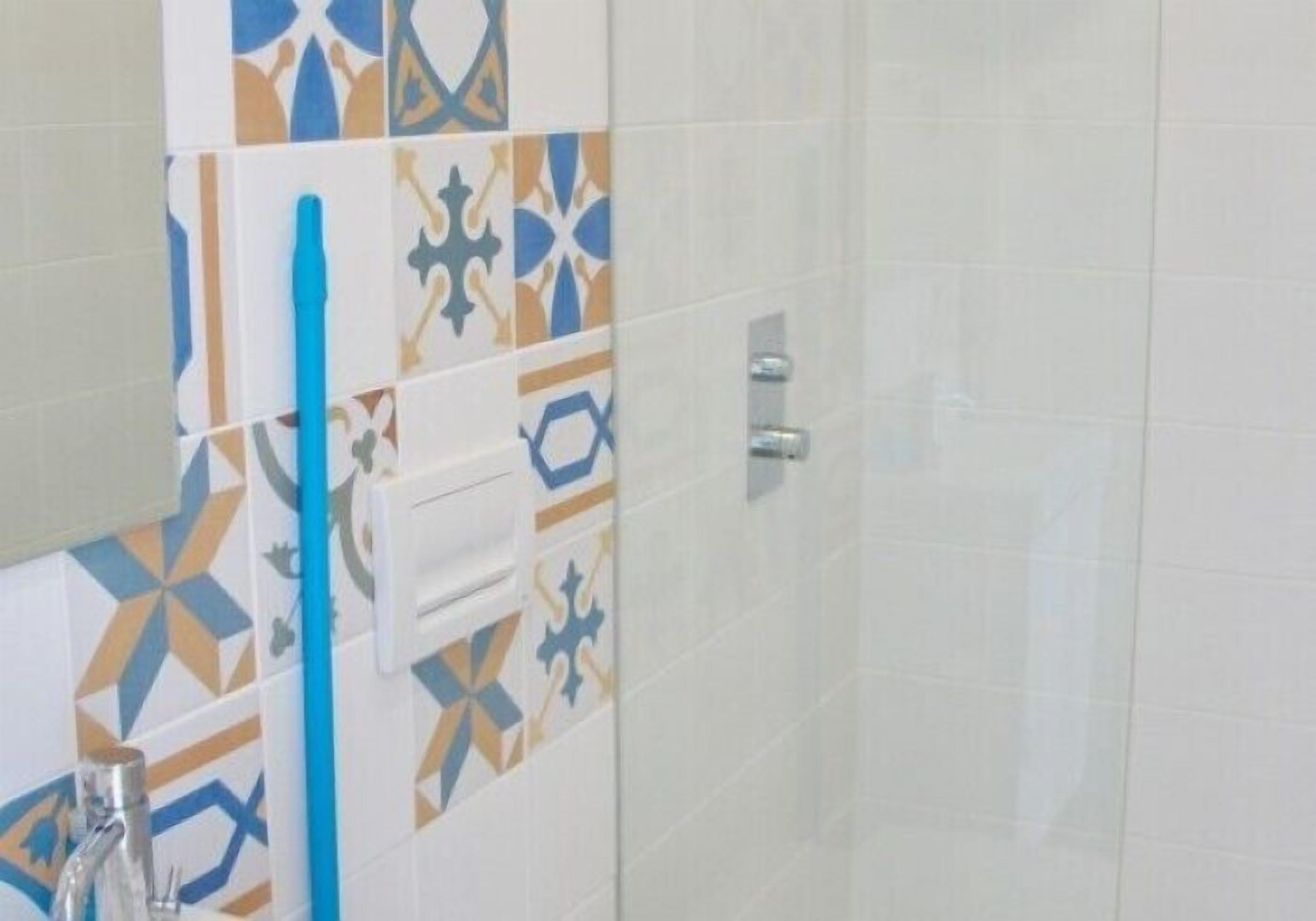 Un baño con baldosas estampadas, un portal cepillos de dientes azul y un perchero para toallas.