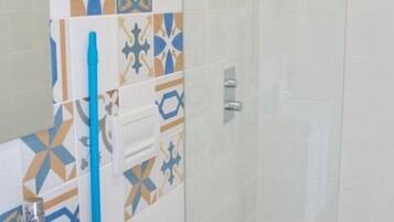 Un baño con baldosas estampadas, un portal cepillos de dientes azul y un perchero para toallas.