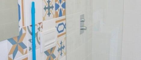 A bathroom with patterned tiles, a blue toothbrush holder, and a towel rack.