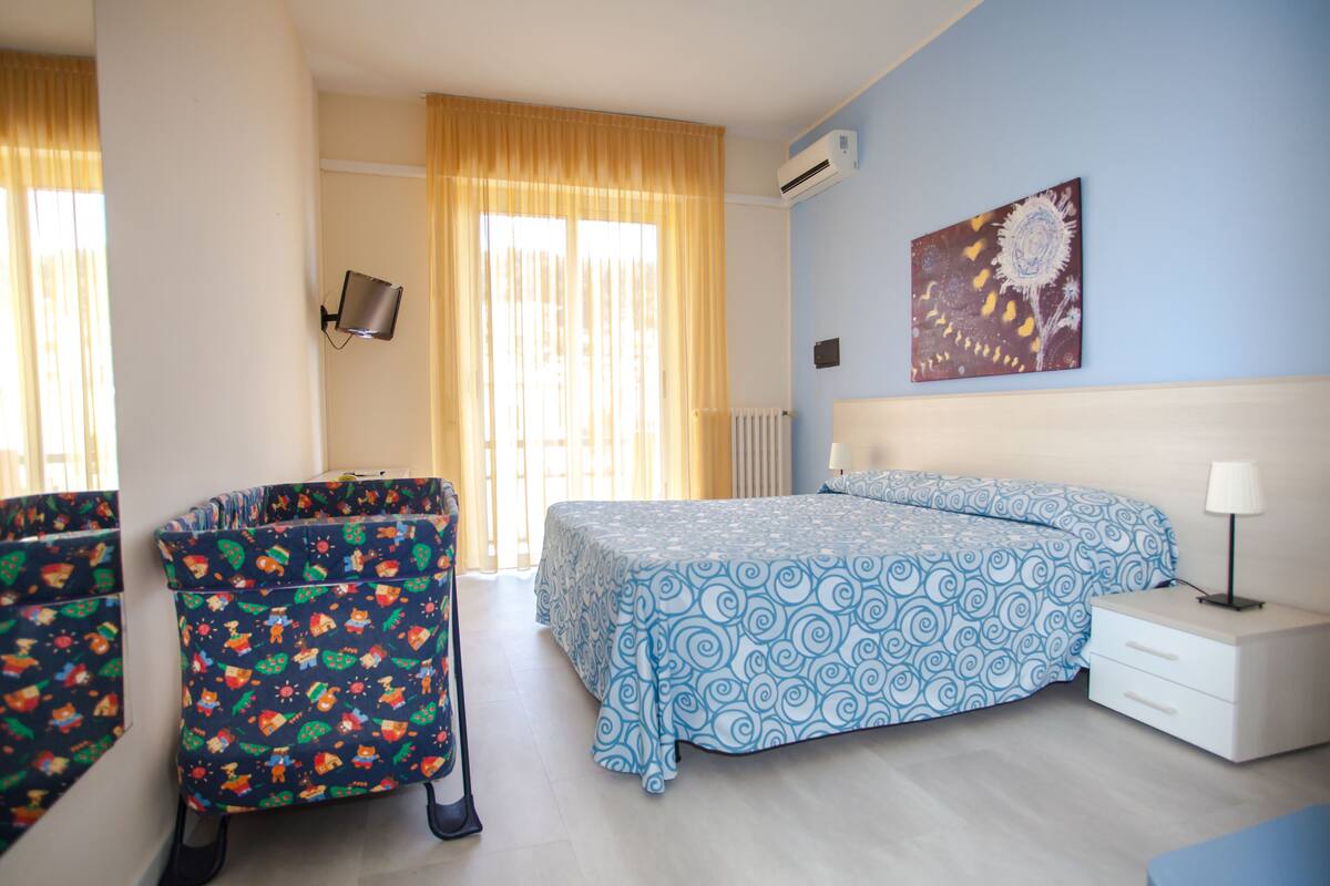 Ein Schlafzimmer mit einem Bett, einem Sessel, einem Nachttisch und einem an der Wand befestigten Fernseher.