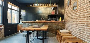 Un café chaleureux avec un mur en pierre rustique, des tables en bois et un mur en briques.