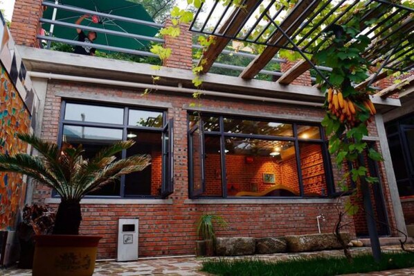 Un bâtiment en briques doté de grandes fenêtres, d’un patio couvert et d’une plante en pot.