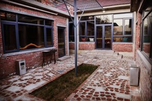 Un bâtiment en briques doté de grandes fenêtres et d’une terrasse carrelée.