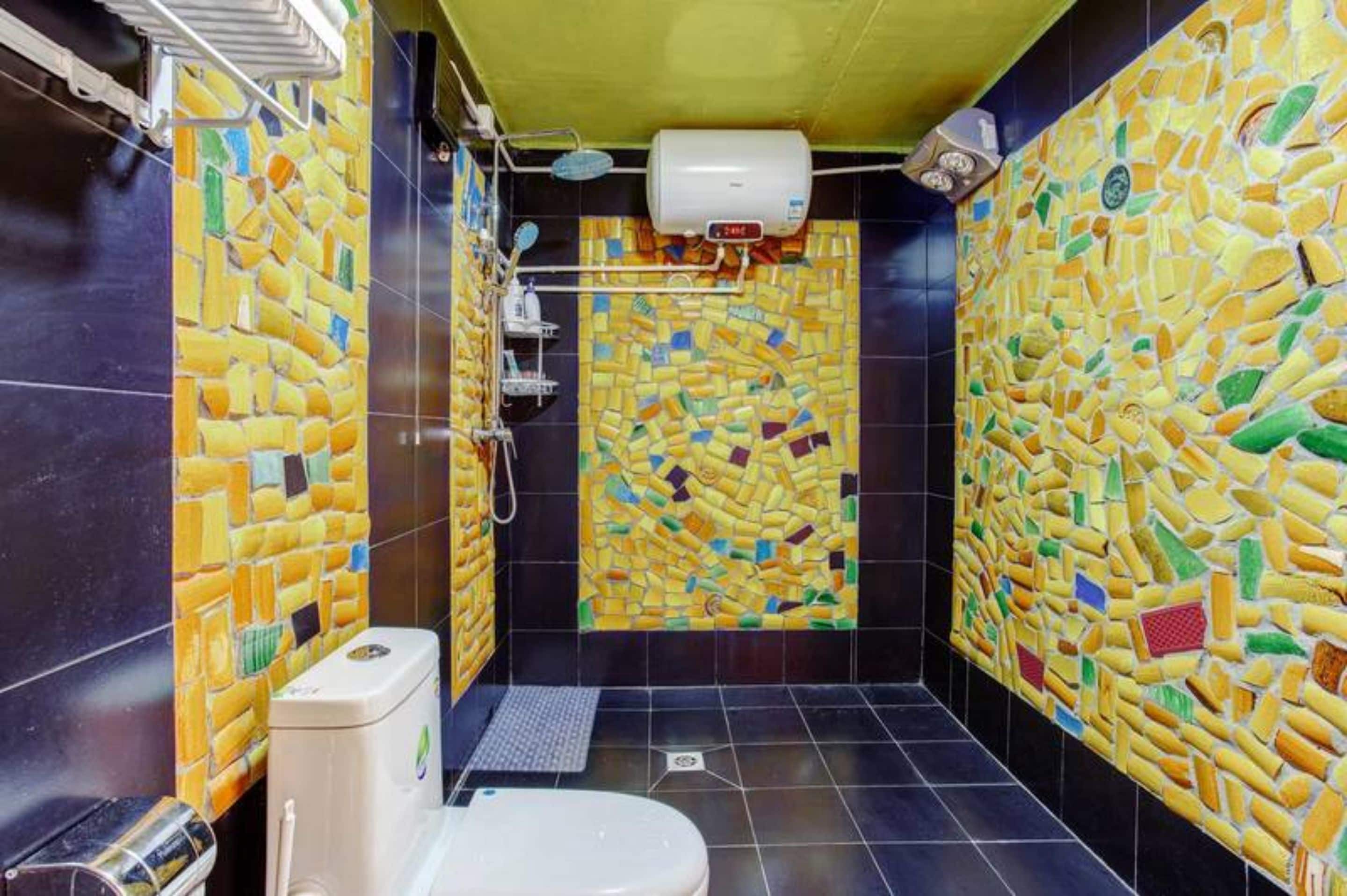 Un baño con paredes de mosaicos y un inodoro.