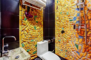 Une salle de bain avec des murs recouverts de mosaïques, des toilettes et un lavabo.