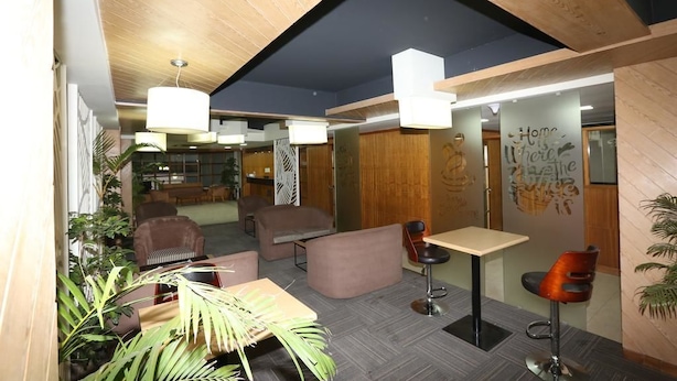 A modern interior with wooden ceiling beams, a seating area with sofas and chairs, and a small table.