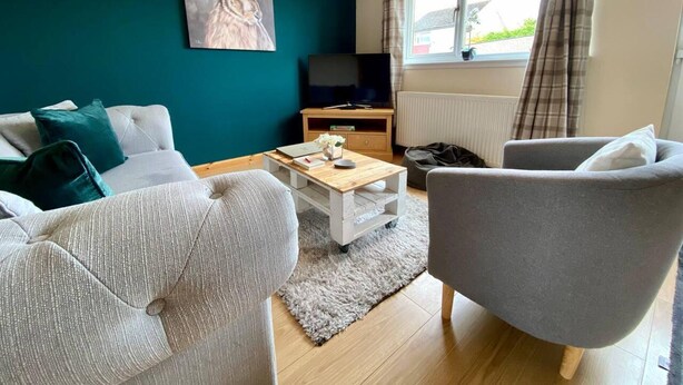 Un salon avec un canapé, un fauteuil, une table basse et un tableau accroché au mur.