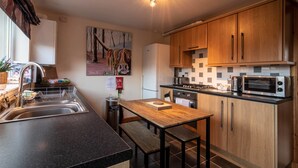 Une cuisine moderne avec des meubles en bois, un évier en acier inoxydable, un four à micro-ondes et une cuisinière à gaz.