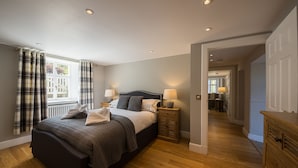 A bedroom with a large bed, bedside lamps, a window with curtains, and a view into another room. - Taymouth Marina - Port Bane (Aberfeldy)