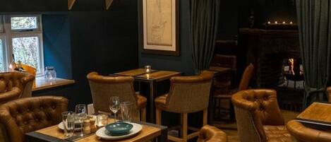 Un acogedor interior de restaurante con sillas de cuero, mesas de madera y una lámpara de araña.