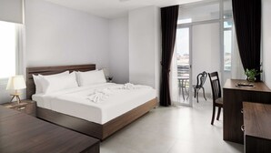 Une chambre d’hôtel moderne dotée d’un grand lit, d’un bureau et d’un balcon avec des chaises.
