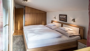 A bedroom with a wooden bed, a nightstand, a wardrobe, and a painting on the wall. - Tannenhof (Kirchberg in Tirol)