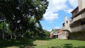 A grassy area with trees and a building with balconies.