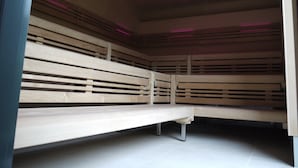 A room with a wooden bench, a ceiling light, and a tiled floor. - Essensio Hotel Düsseldorf (Erkrath)