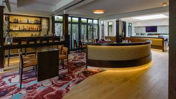 A modern bar area with a curved counter, seating, and a large window providing natural light.