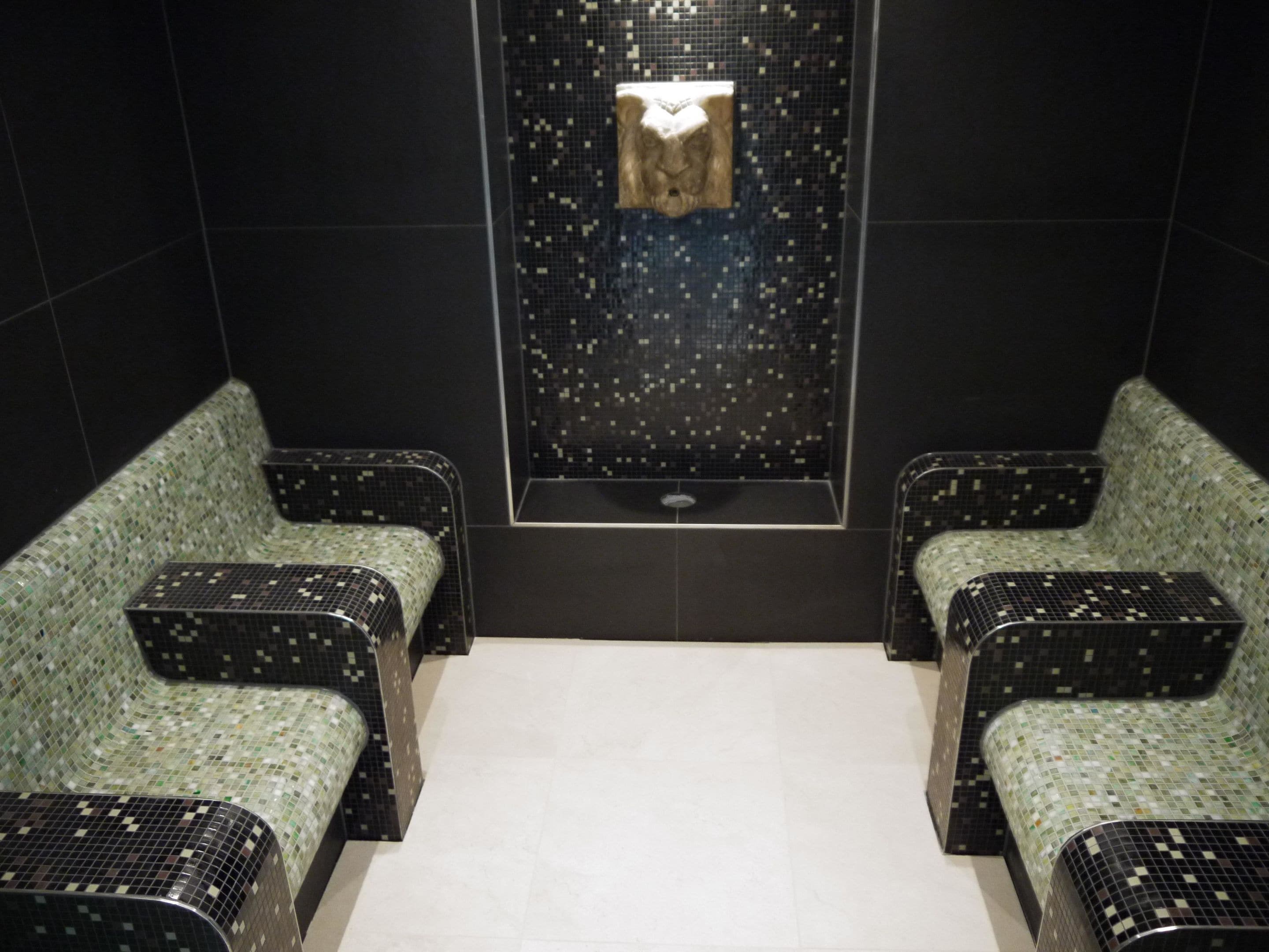 Baño con dos lavamanos, un secador de manos y un espejo.