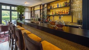 Een bar met een lange toonbank, meerdere planken vol flessen en uitzicht op het buiten.