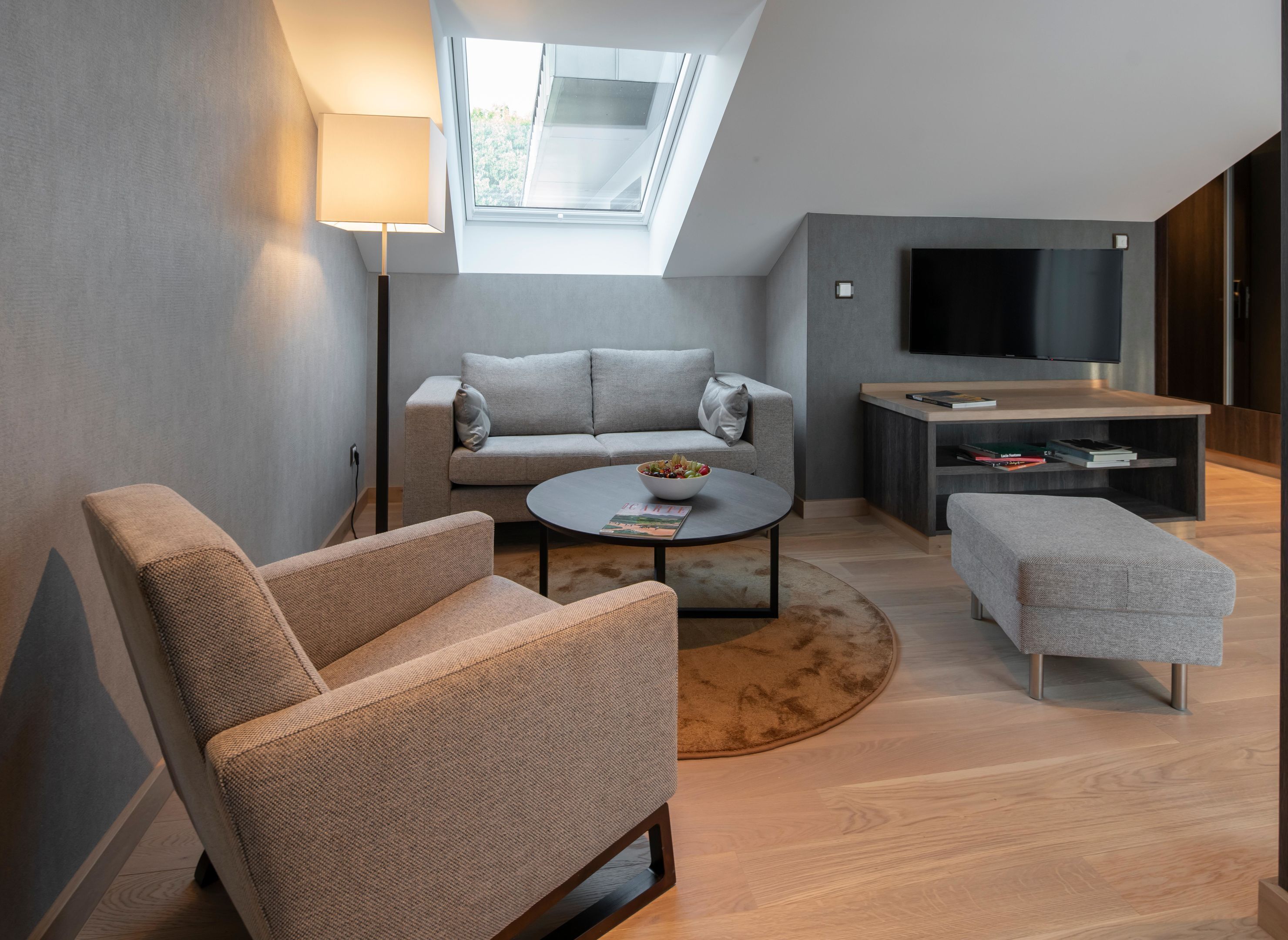 A modern living room with a sofa, armchair, coffee table, and a TV.