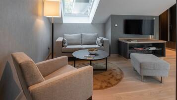 A modern living room with a sofa, armchair, coffee table, and a TV.