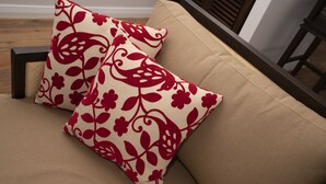 A beige sofa with two decorative pillows featuring a red floral pattern. - The best Byron Bay has to offer - stunning views, total luxury and style.   (Coopers Shoot)