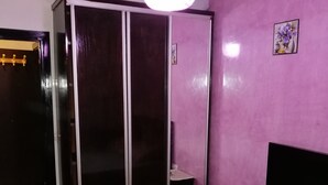 Une chambre à coucher comprenant un lit, une armoire, une table de chevet et un luminaire suspendu.