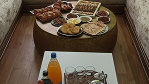Un salon comprenant un ensemble de canapés, une table basse avec des collations et des boissons, et une fenêtre décorée.
