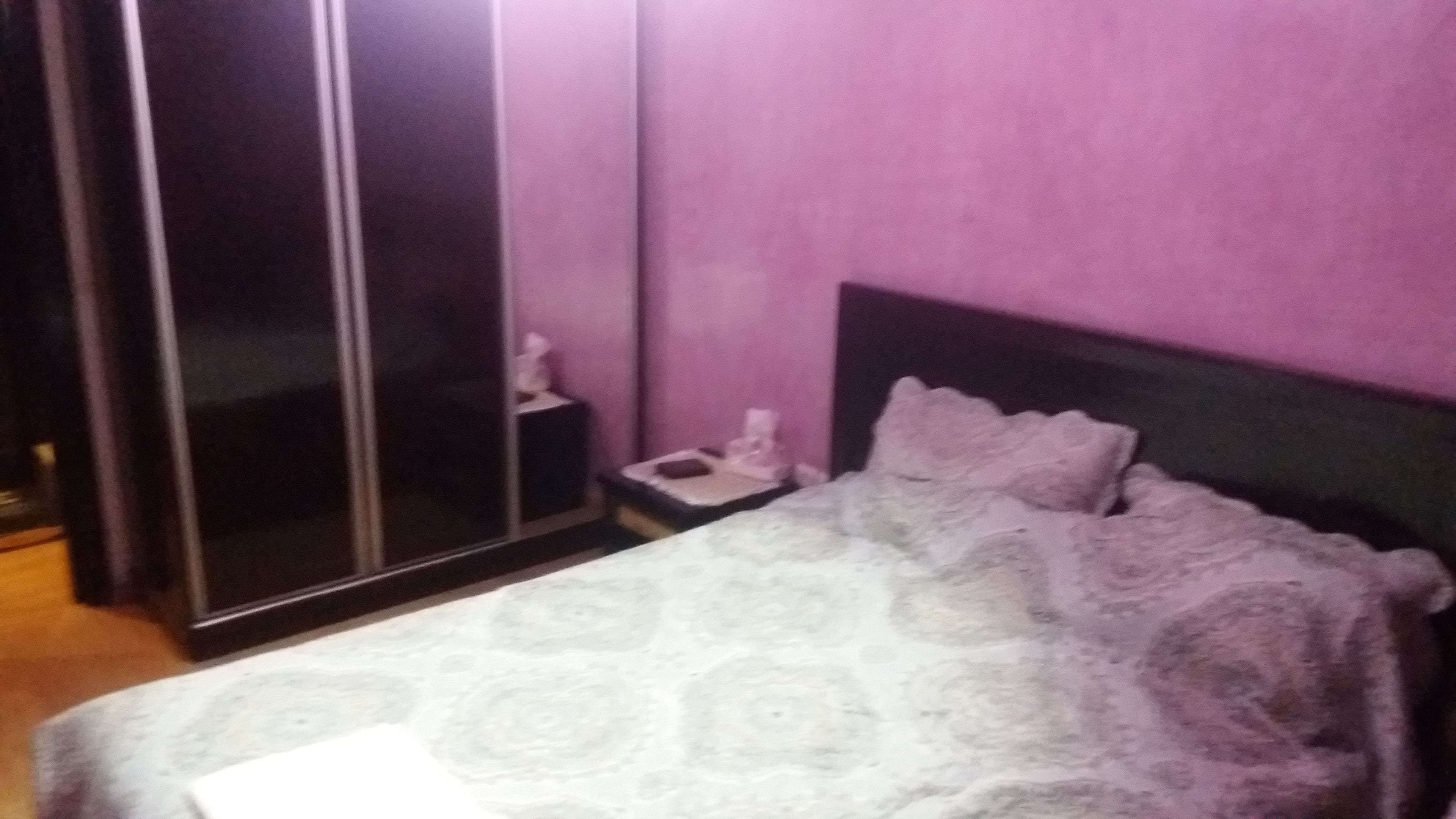 A bedroom with a bed, a nightstand, and a wardrobe.